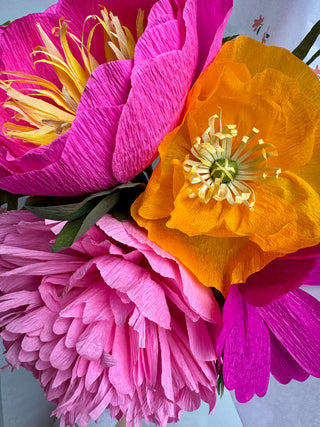 Close-up of pink and orange paper flowers with green stems.