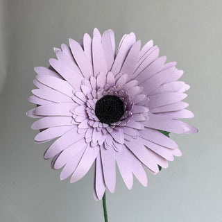 Light purple gerber daisy with a black center handcrafted from cardstock paper and finished with crepe paper leaf.