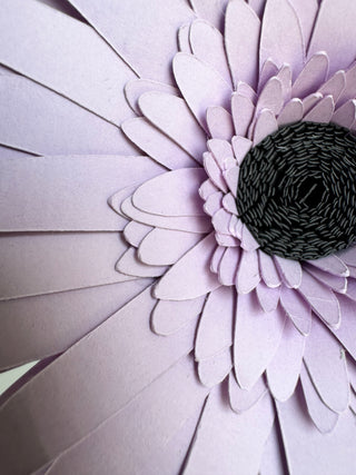 Close-up of cardstock gerber daisy with a black center on a light gray background