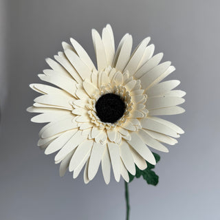 White gerber daisy with a black center handcrafted from cardstock paper and finished with crepe paper leaf.