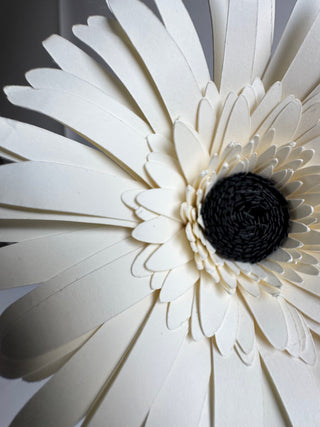 Close-up of cardstock gerber daisy with a black center on a light gray background