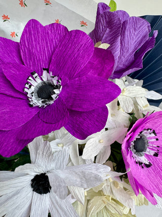 close up of purple and white flowers with a fan in the background