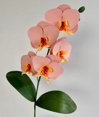 Handcrafted pink paper orchids with yellow and magenta centers on a gray background